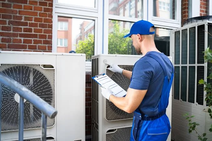 HVAC technician inspecting outdoor air conditioning units with a maintenance checklist