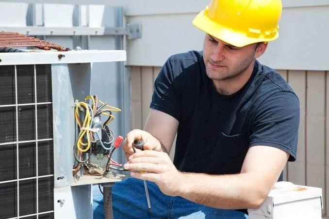 Technician inspecting wiring in an outdoor air conditioning unit