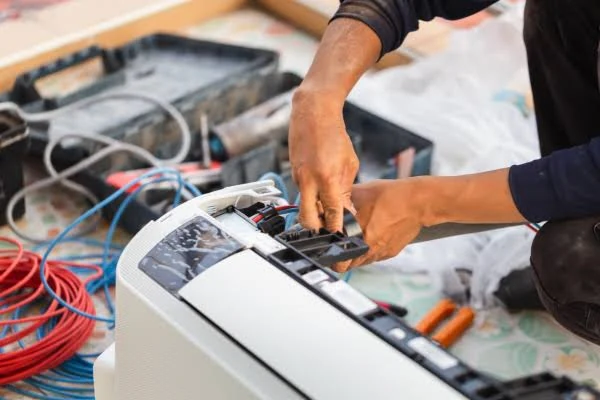 Technician checking an indoor air conditioning unit and its electrical controls