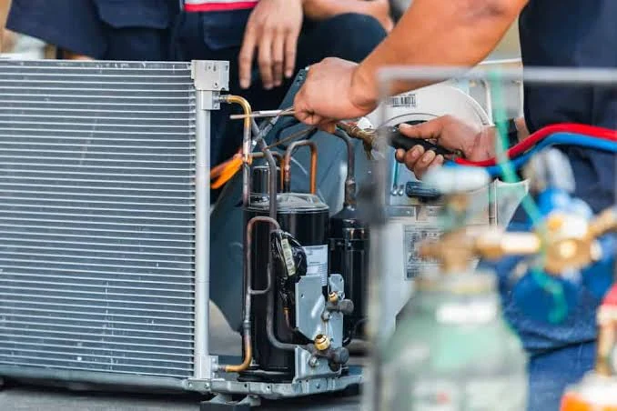 Technician working on air conditioning system components and refrigerant lines